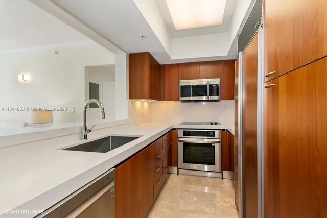 a kitchen with stainless steel appliances granite countertop a sink and a stove top oven with wooden floor