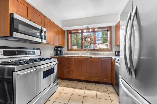 a kitchen with stainless steel appliances granite countertop a stove top oven a refrigerator and a sink