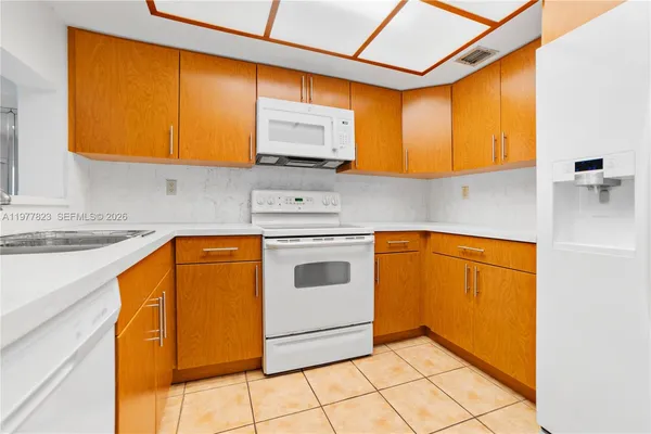 a kitchen with a sink a stove top oven cabinets and a window