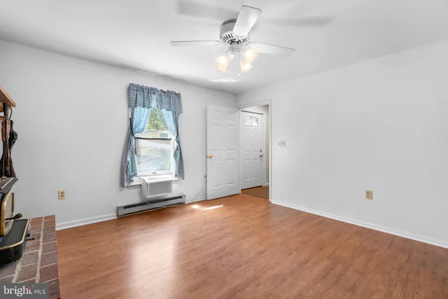 an empty room with wooden floor chandelier fan and windows