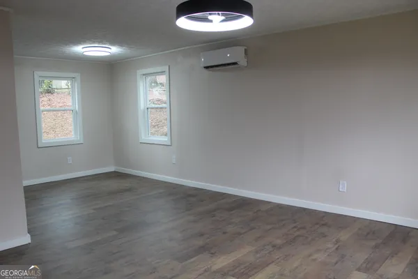 an empty room with windows and chandelier fan
