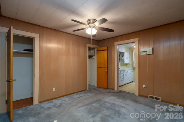 an empty room with closet and a chandelier fan