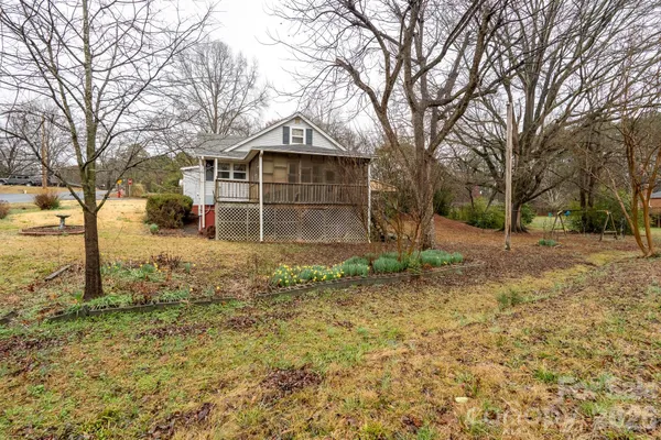 a view of a house with a yard and large trees