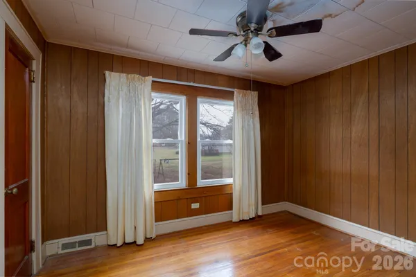 a view of an empty room with a window and wooden floor
