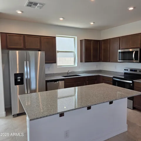 a kitchen with stainless steel appliances granite countertop a refrigerator a sink a stove a microwave and island