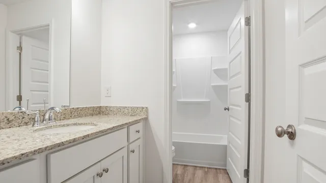 a bathroom with a granite countertop sink a mirror and a shower