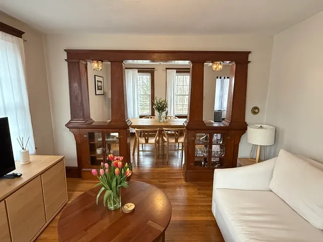 a living room with furniture a chandelier and wooden floor
