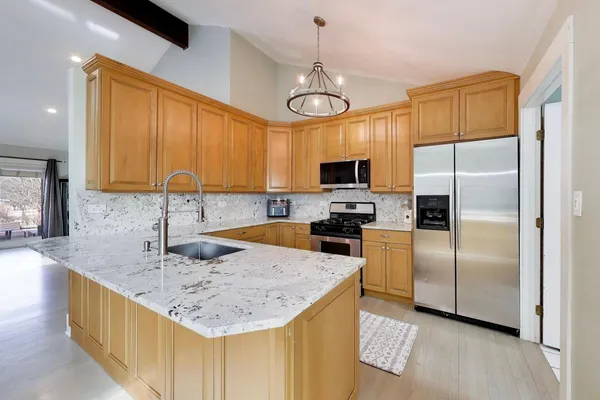 a kitchen with stainless steel appliances granite countertop a sink a stove and refrigerator