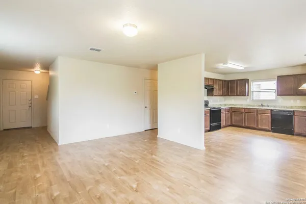 a view of a kitchen with a sink and dishwasher a refrigerator with white cabinets