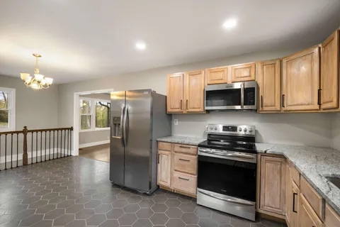 a kitchen with stainless steel appliances granite countertop a stove a sink a microwave a refrigerator and cabinets
