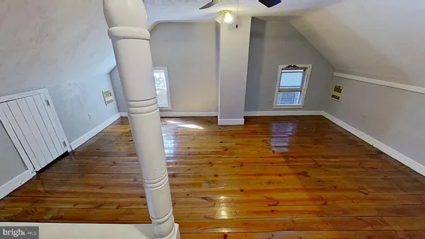 a view of an empty room with wooden floor and staircase