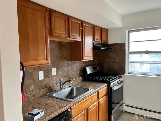a kitchen with granite countertop a sink stove and cabinets