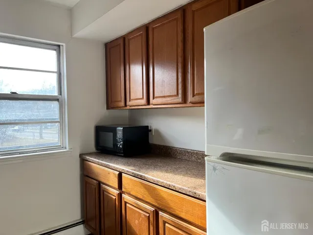 a kitchen with stainless steel appliances granite countertop white cabinets and a window