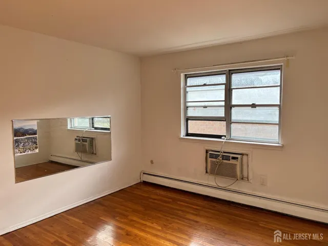 an empty room with wooden floor cabinet and windows