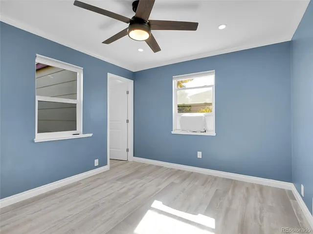 a view of an empty room with window and ceiling fan