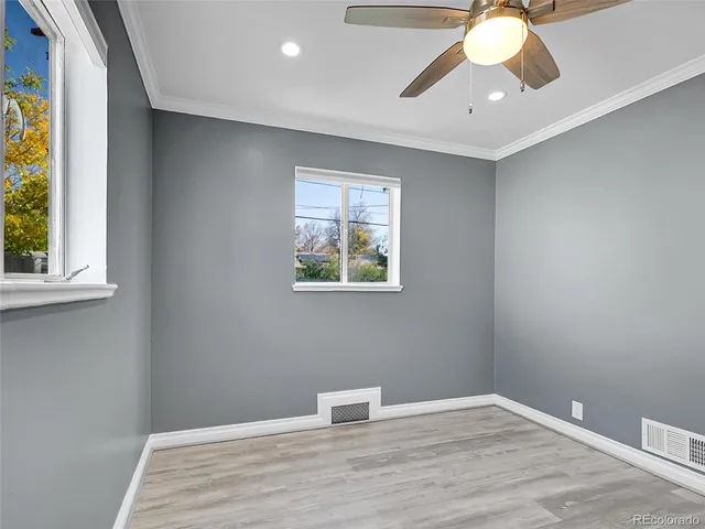 a view of an empty room with window and wooden floor