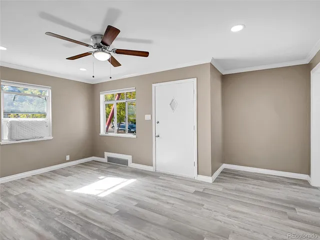 a view of an empty room with window and wooden floor