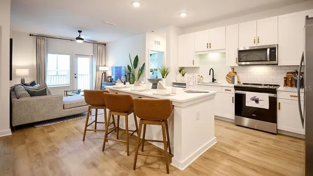 a kitchen with a sink stove and white cabinets with wooden floor