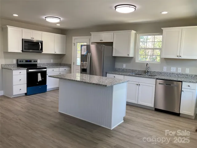 a kitchen with stainless steel appliances granite countertop a stove a sink dishwasher a refrigerator and a microwave oven with wooden floor