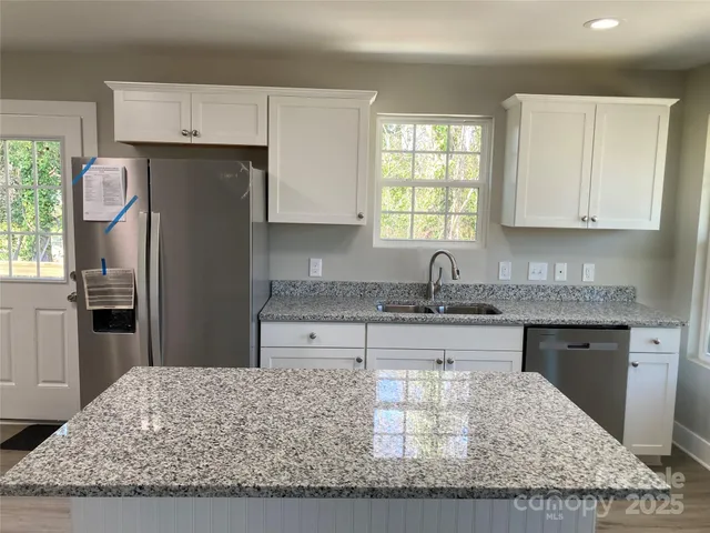a kitchen with granite countertop a sink stove and refrigerator