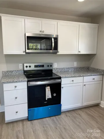 a kitchen with granite countertop white cabinets and stainless steel appliances
