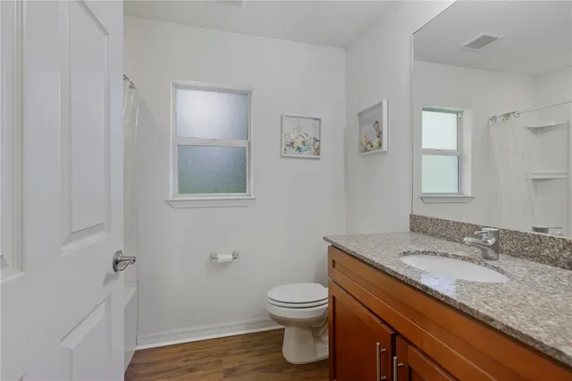 a bathroom with a granite countertop toilet a sink and a mirror