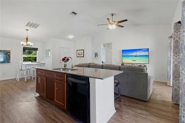 a kitchen with stainless steel appliances granite countertop a sink dishwasher and a stove with wooden floor