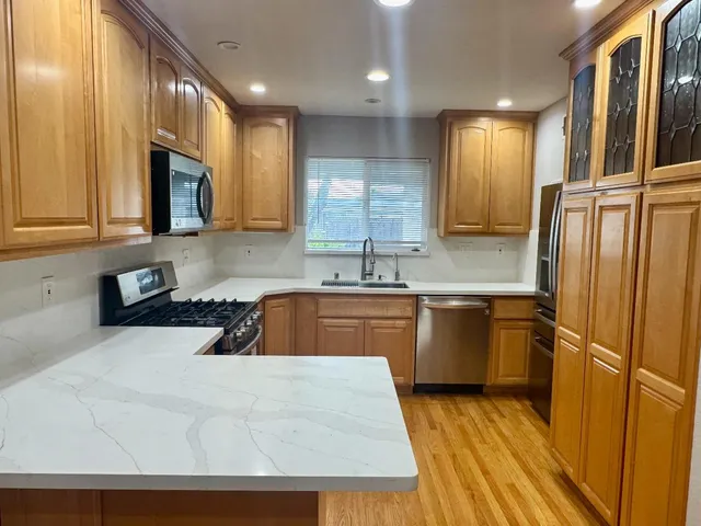 a kitchen with stainless steel appliances granite countertop a refrigerator a sink dishwasher a stove with wooden cabinets and floor