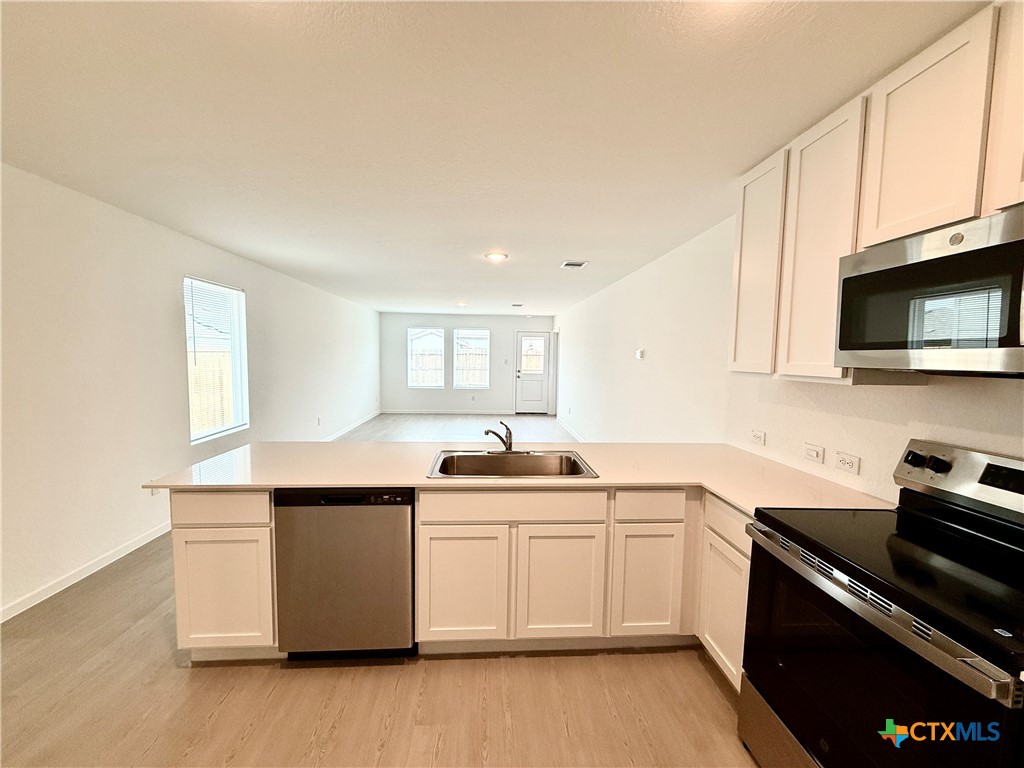 413 Moscato Road New Braunfels, TX 78130 - Photo 6 of 28 a kitchen with stainless steel appliances a sink stove and microwave