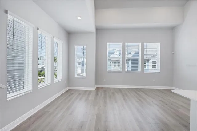 a large kitchen with kitchen island a sink a stove a refrigerator and white cabinets with wooden floor