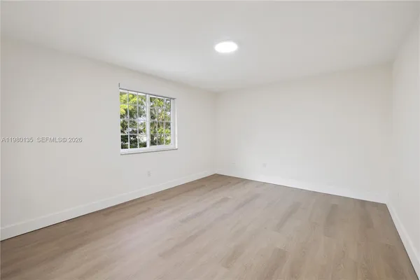 an empty room with wooden floor and window