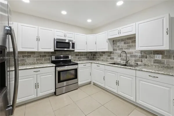 a kitchen with granite countertop white cabinets and stainless steel appliances