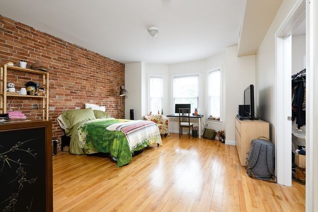 a spacious bedroom with a bed and wooden floor