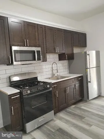 a kitchen with granite countertop a stove a microwave a sink and cabinets