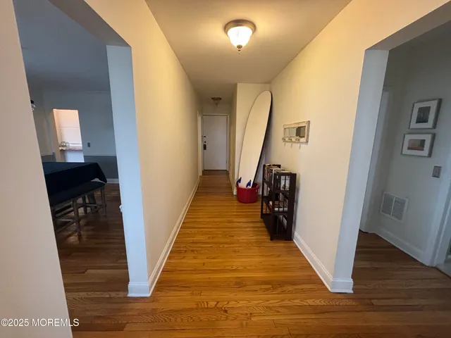 a view of a hallway with wooden floor and stairs