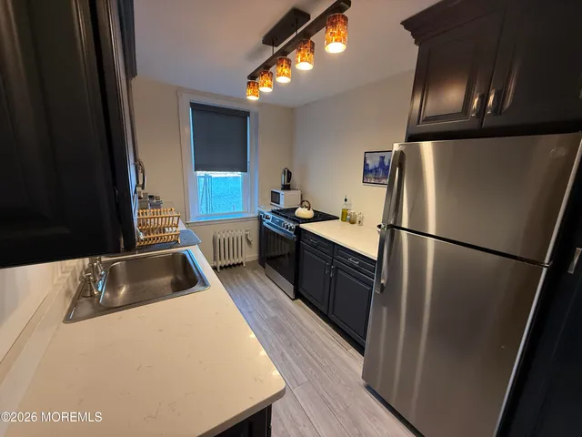 a kitchen with granite countertop a refrigerator a sink a stove and cabinets