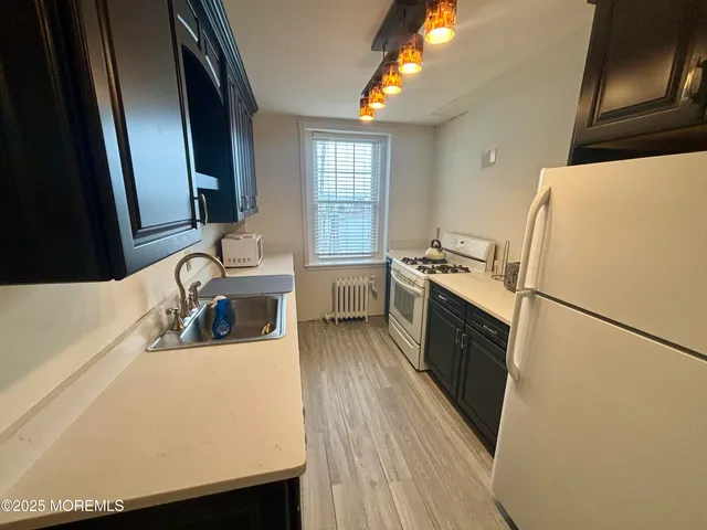 a kitchen with a refrigerator a sink and wooden floor