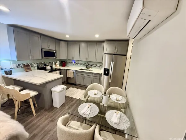 a kitchen with stainless steel appliances granite countertop a refrigerator a sink a stove a dining table and chairs with wooden floor