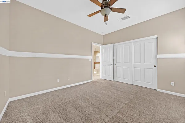 an empty room with windows and ceiling fan