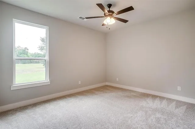 an empty room with a window and a fan