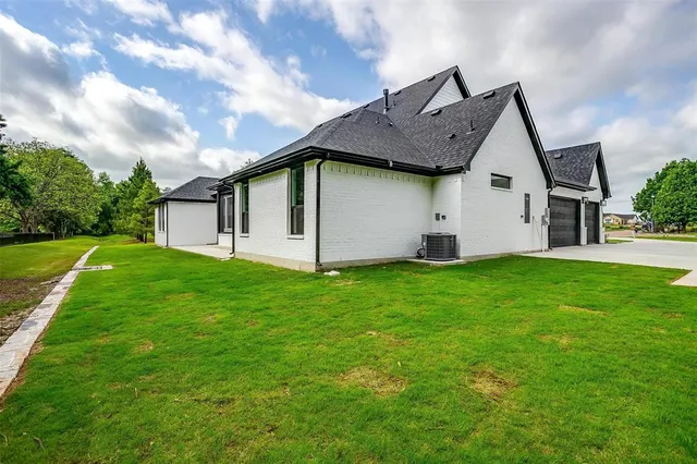 a view of a house with a big yard potted plants and large tree