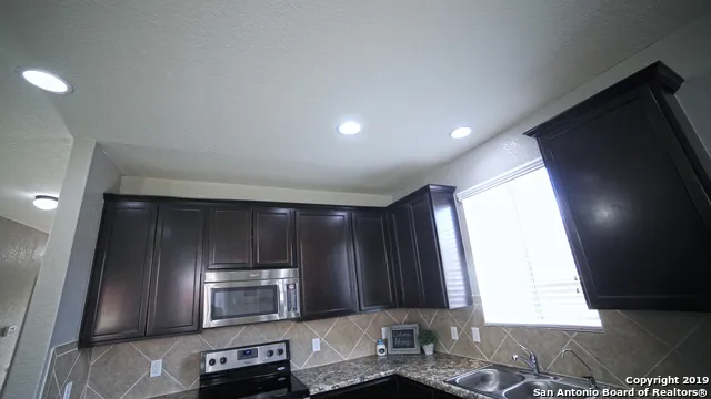 a kitchen with a sink a microwave a refrigerator and cabinets