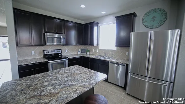 a kitchen with stainless steel appliances granite countertop a refrigerator a stove a sink and a microwave