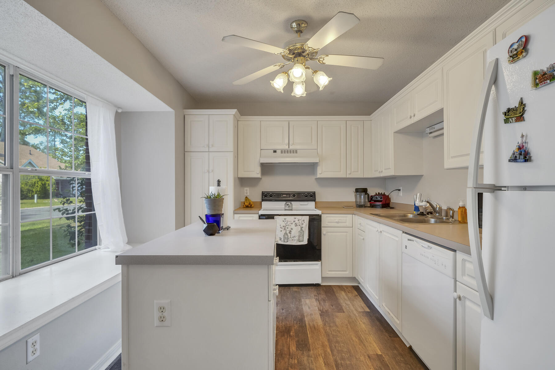 504 Easy Street Fort Walton Beach, FL 32547 - Photo 6 of 21 a kitchen with a refrigerator a stove a sink dishwasher and white cabinets with wooden floor