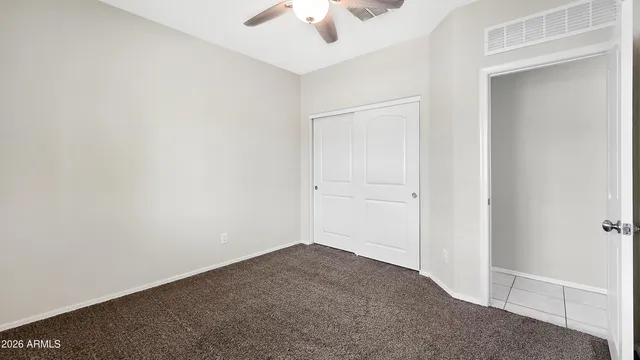 an empty room with a ceiling fan and carpet