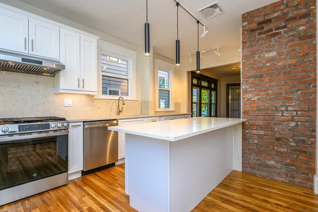 a kitchen with stainless steel appliances granite countertop a sink a stove and a wooden floor