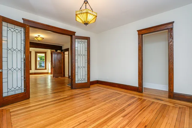 an empty room with wooden floor and chandelier