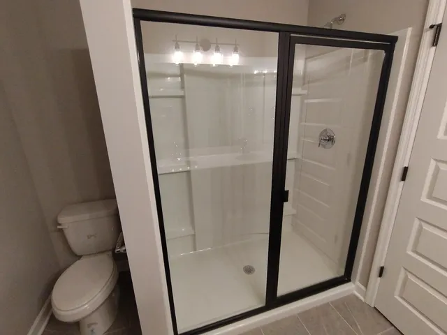 a bathroom with a glass shower door and toilet