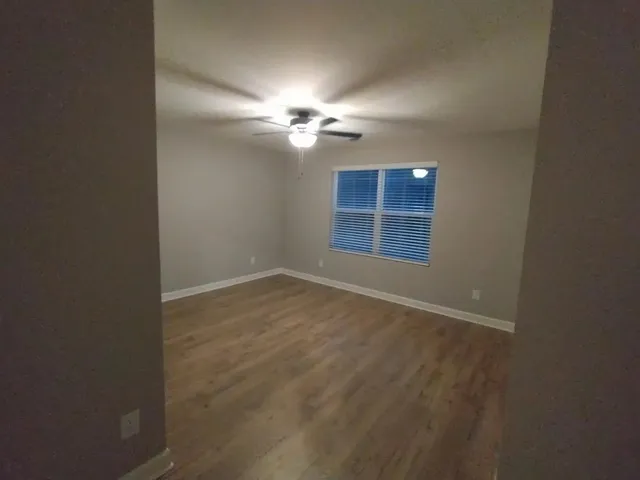 an empty room with windows and fan