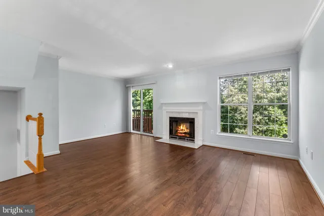 an empty room with wooden floor fireplace and windows
